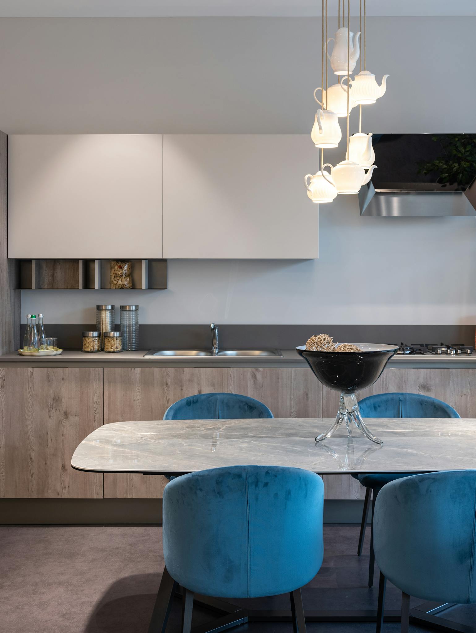 Interior of modern kitchen with chairs near table with bowl and cabinet and kitchenware near sink